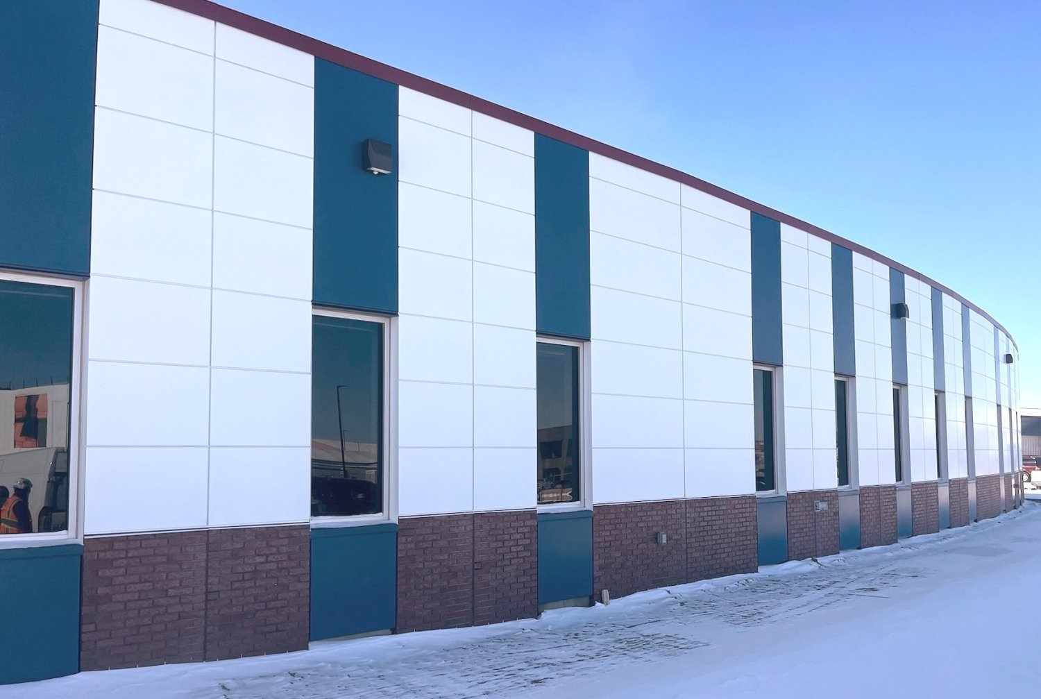CLADLOK™ panels — white and teal ACM panels on curved arena facade in winter