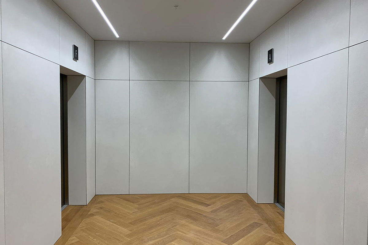 Petrarch engineered stone interior wall panels — lift lobby with herringbone floor