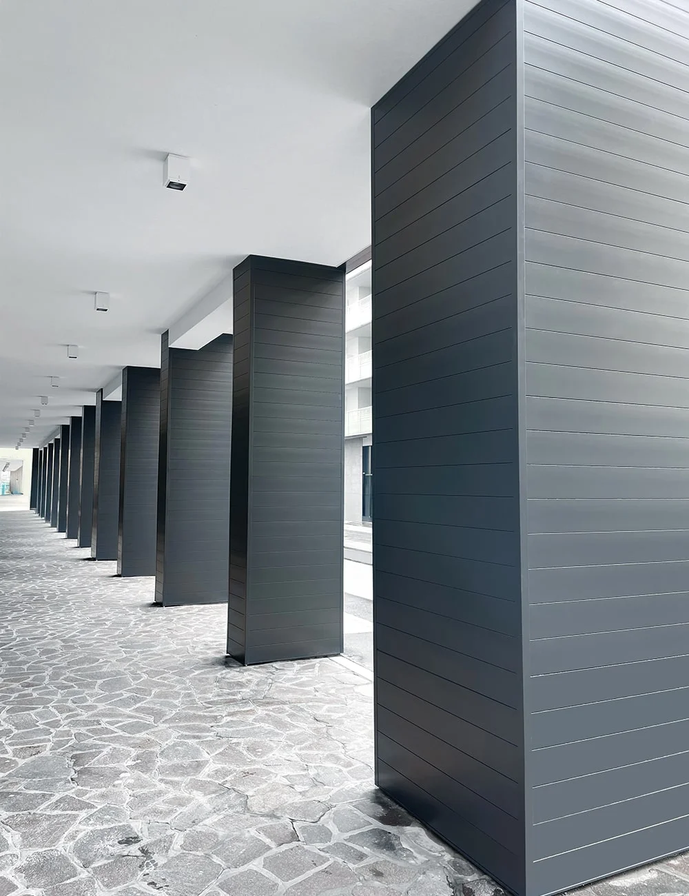 ForMe Design aluminum battens — covered walkway with dark columns